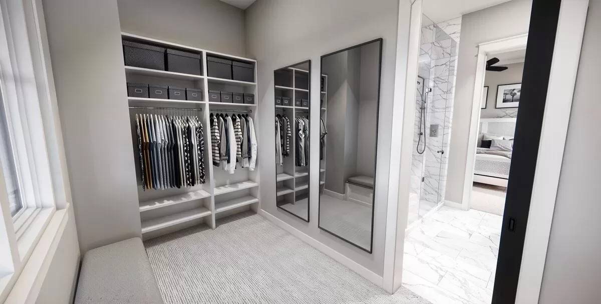 Primary walk-in closet with ample storage, a cushioned bench, and a couple of full-length mirrors.