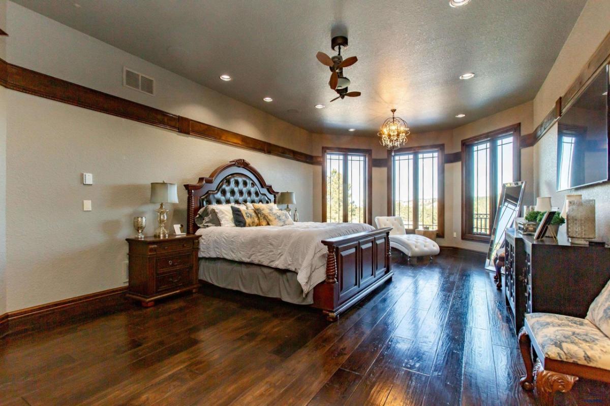 Bedroom with a large bed, wood flooring and glass windows.