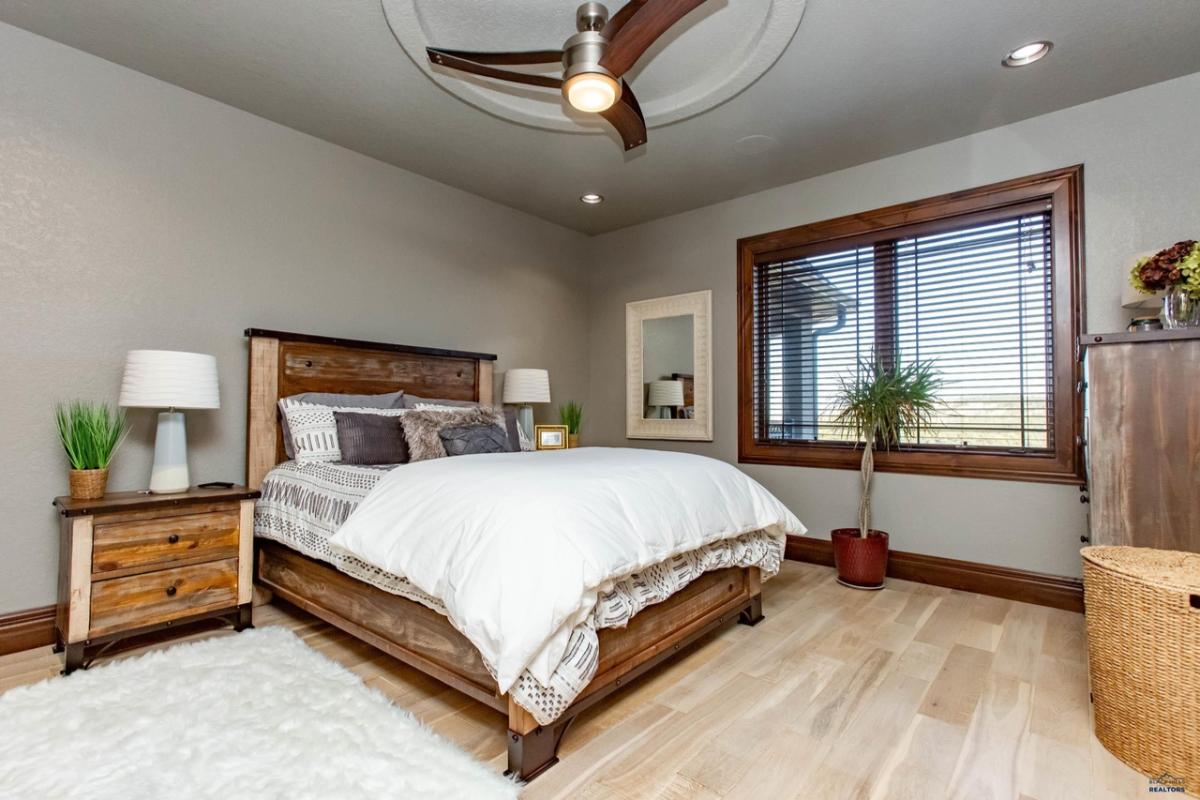 Bedroom with a large bed, wood flooring and glass windows.