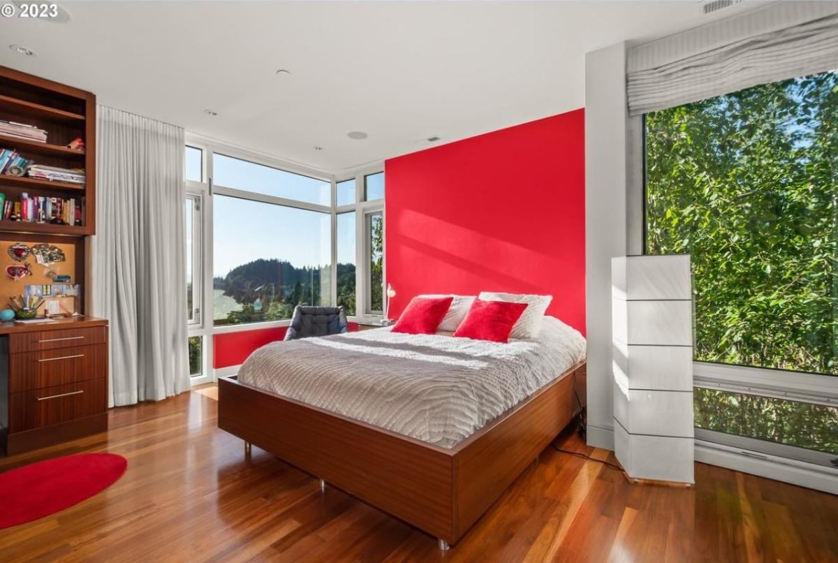 Bedroom with a large bed, wood flooring and glass windows.