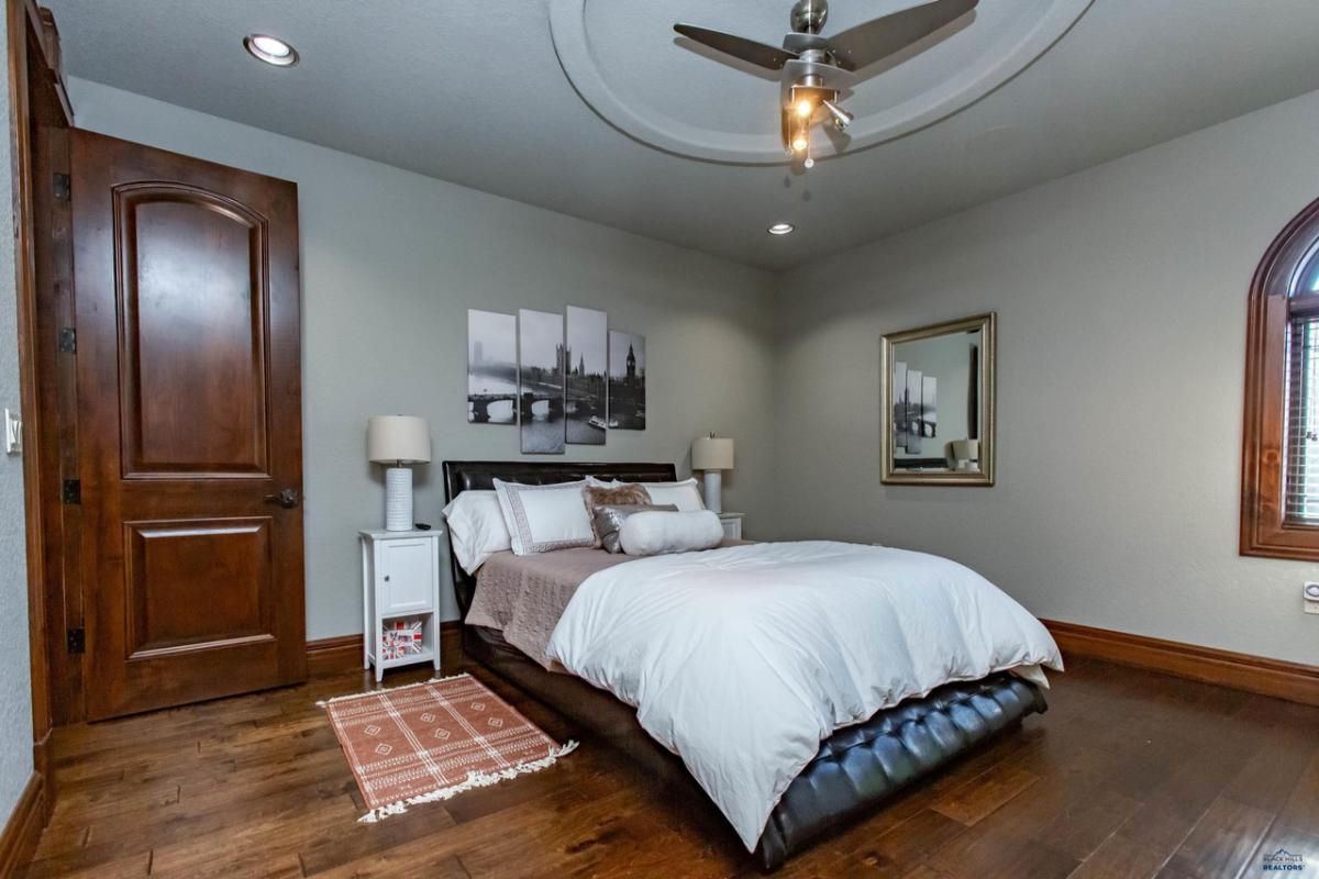 Bedroom with a large bed, wood flooring and a ceiling fan.