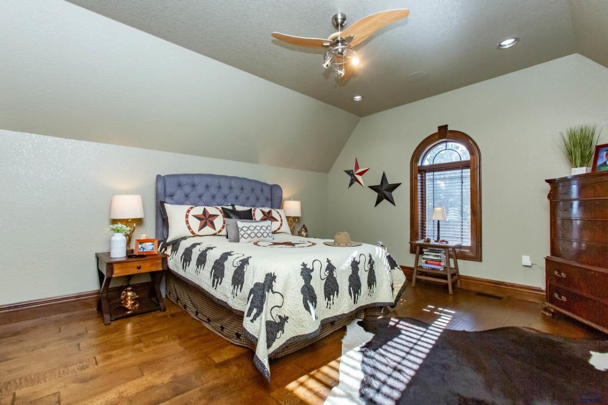 Bedroom with a large bed, wood flooring and glass windows.