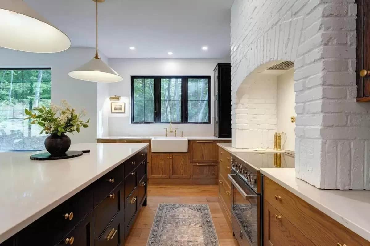 Kitchen with wooden cabinets, quartz countertops, and a farmhouse sink under the trio of windows.