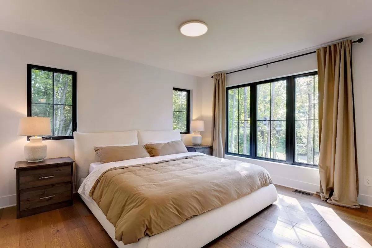 Primary bedroom with wooden nightstands and a platform bed over the wide-plank flooring.