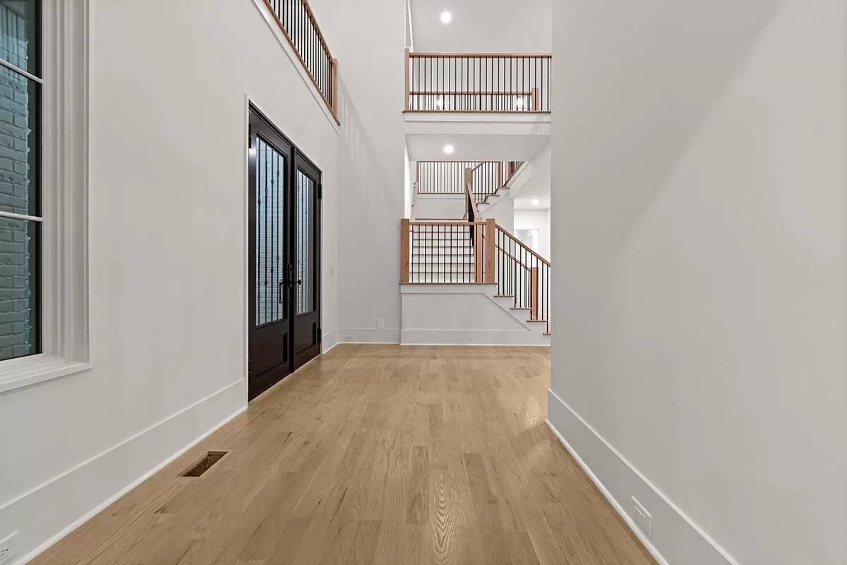 Foyer with a French front door and hardwood flooring.