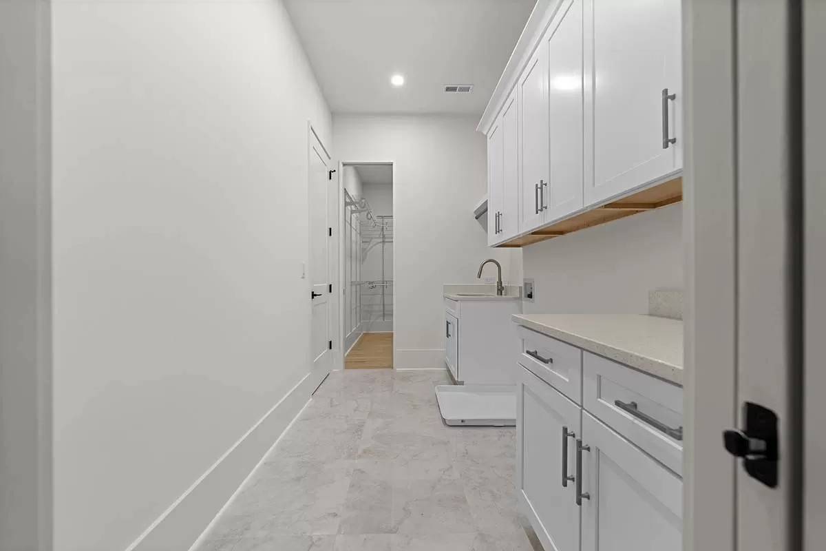 Laundry room with white cabinets and a utility sink.