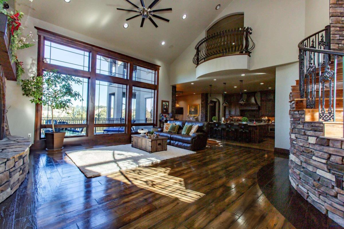 Living room with a couch, wood flooring and large glass walls.