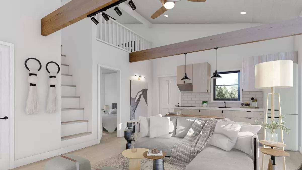 The living room and kitchen includes a view of the balcony and a vaulted ceiling lined with exposed beams.