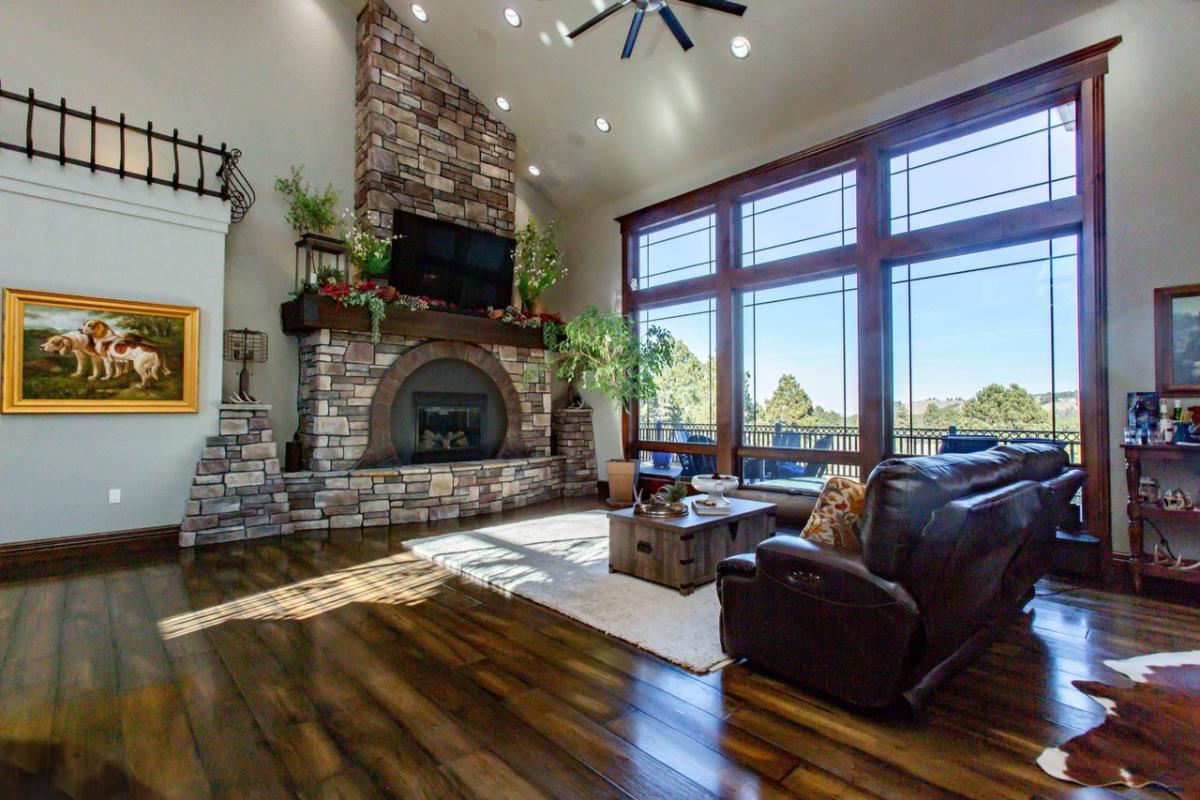 Living room with a couch, fireplace, wood flooring and large glass walls.