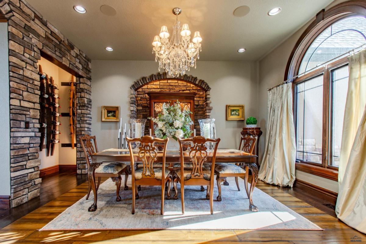 Dining room with a large wood table, wood flooring and a chandelier.