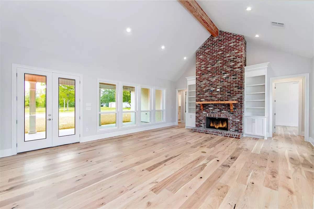 Great room with a brick fireplace and a cathedral ceiling lined with an exposed beam.