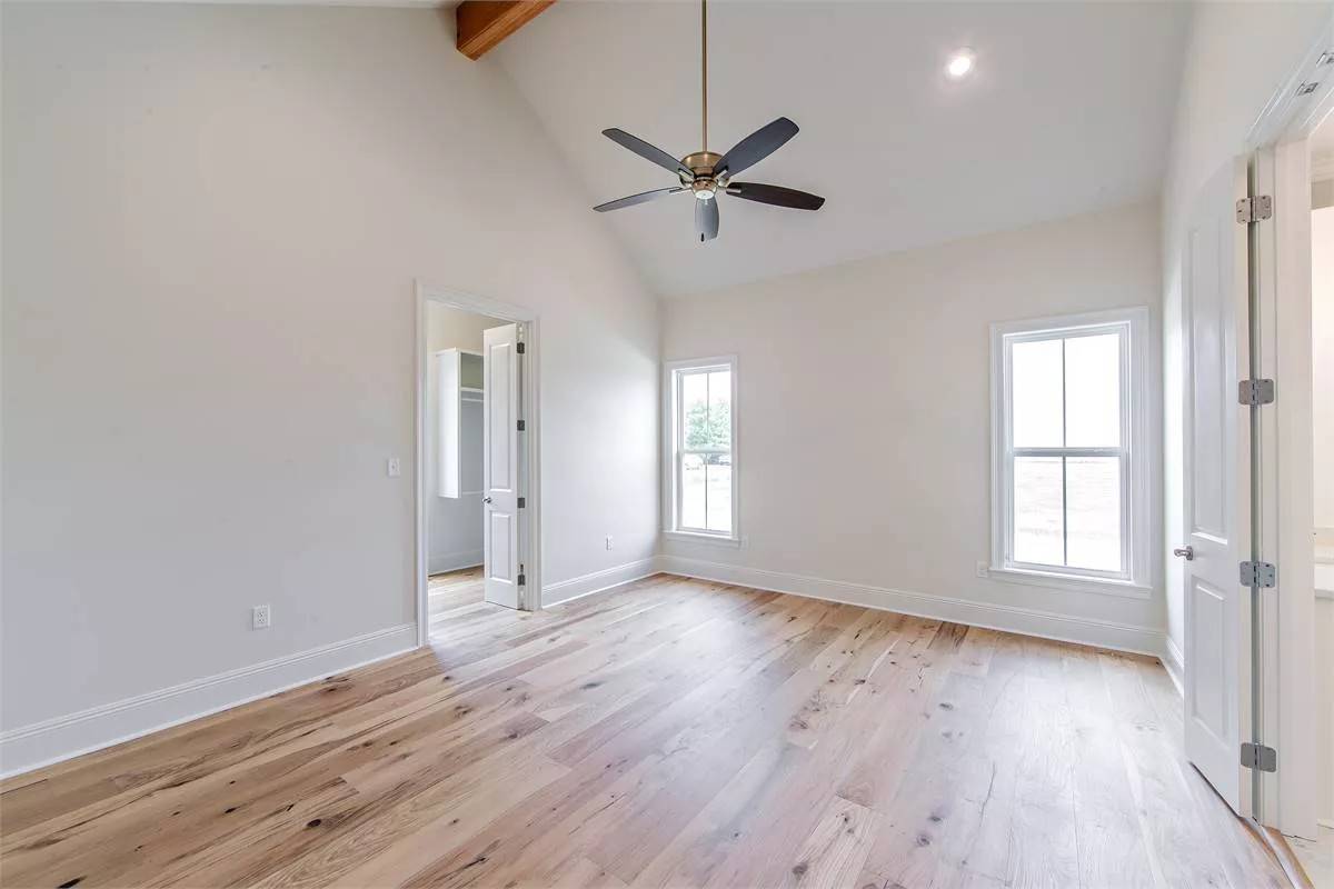 Primary bedroom with a hardwood floor and a vaulted ceiling.