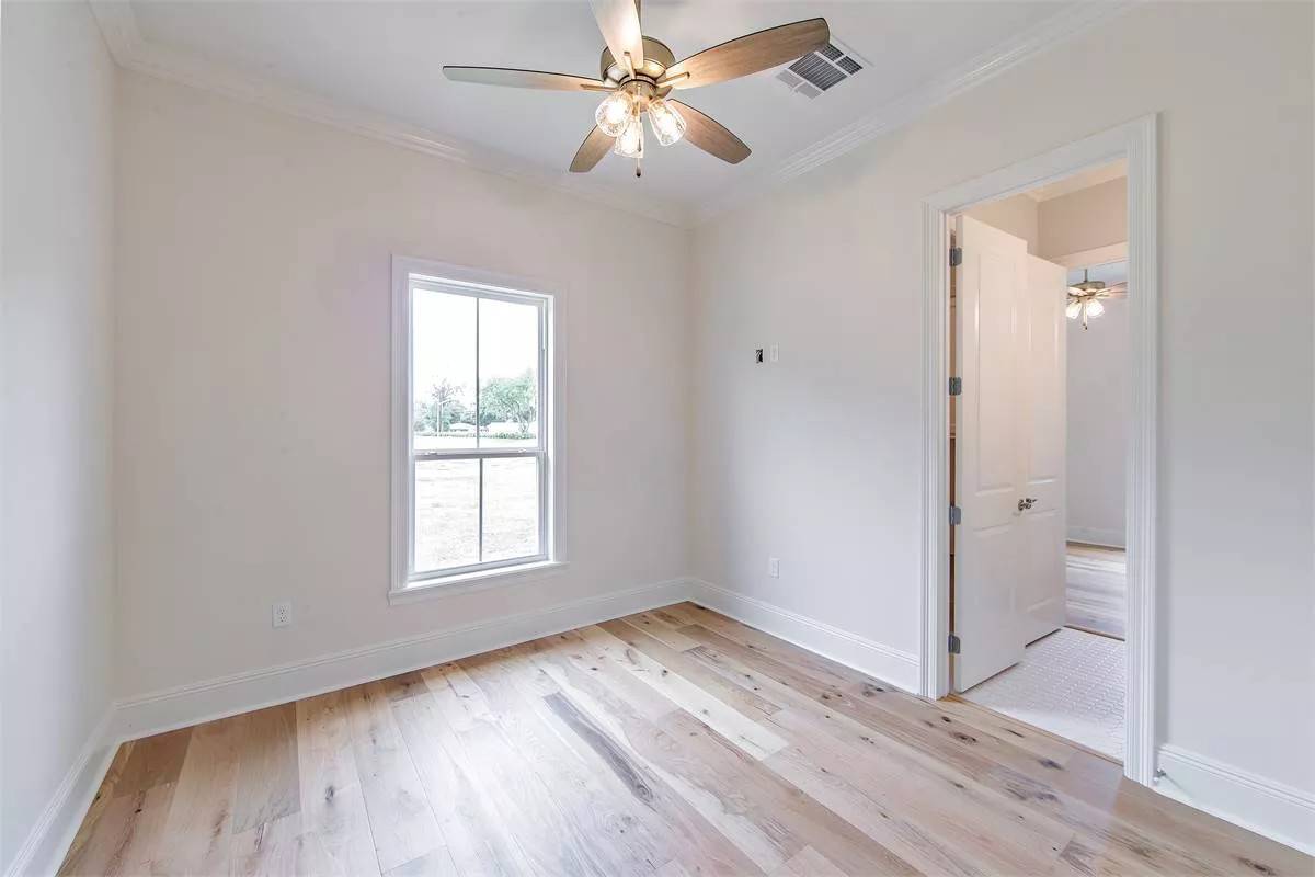 Bedroom with beige walls and hardwood flooring.