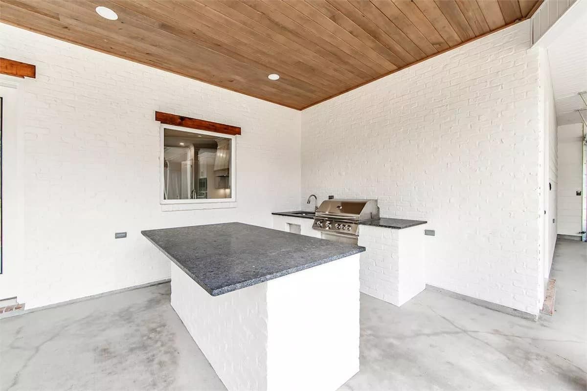 Covered porch with outdoor kitchen under a wood-paneled ceiling.
