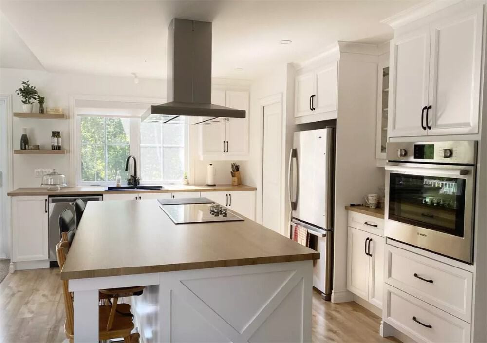 Kitchen with white cabinets, modern appliances, and a cooktop island.