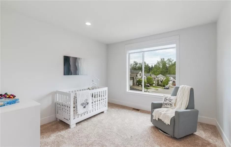 Nursery room with a white crib and a gray armchair.
