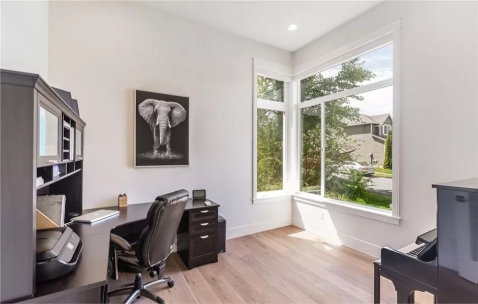 Office with dark wood furnishings over the wide plank flooring.