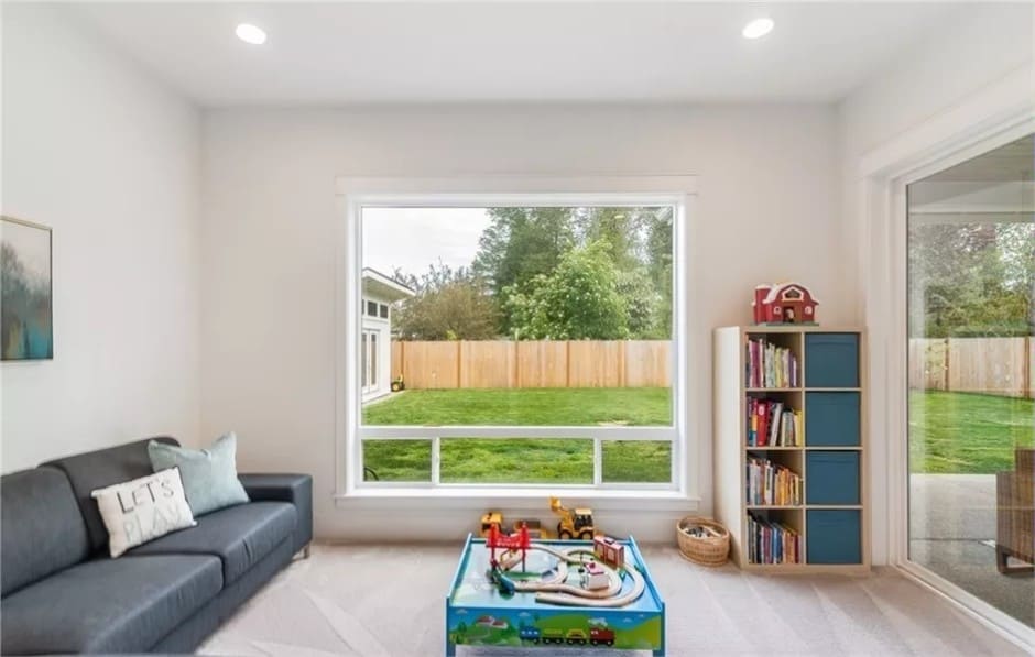 Playroom with a sectional sofa, a carpeted floor, and huge windows.