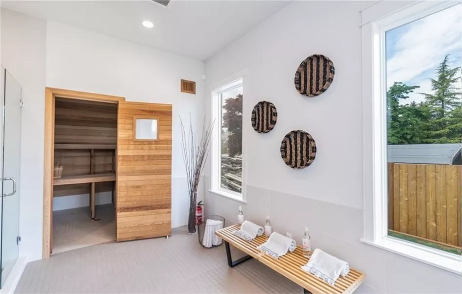 Sauna with a sitting area and white walls adorned by round wall arts.
