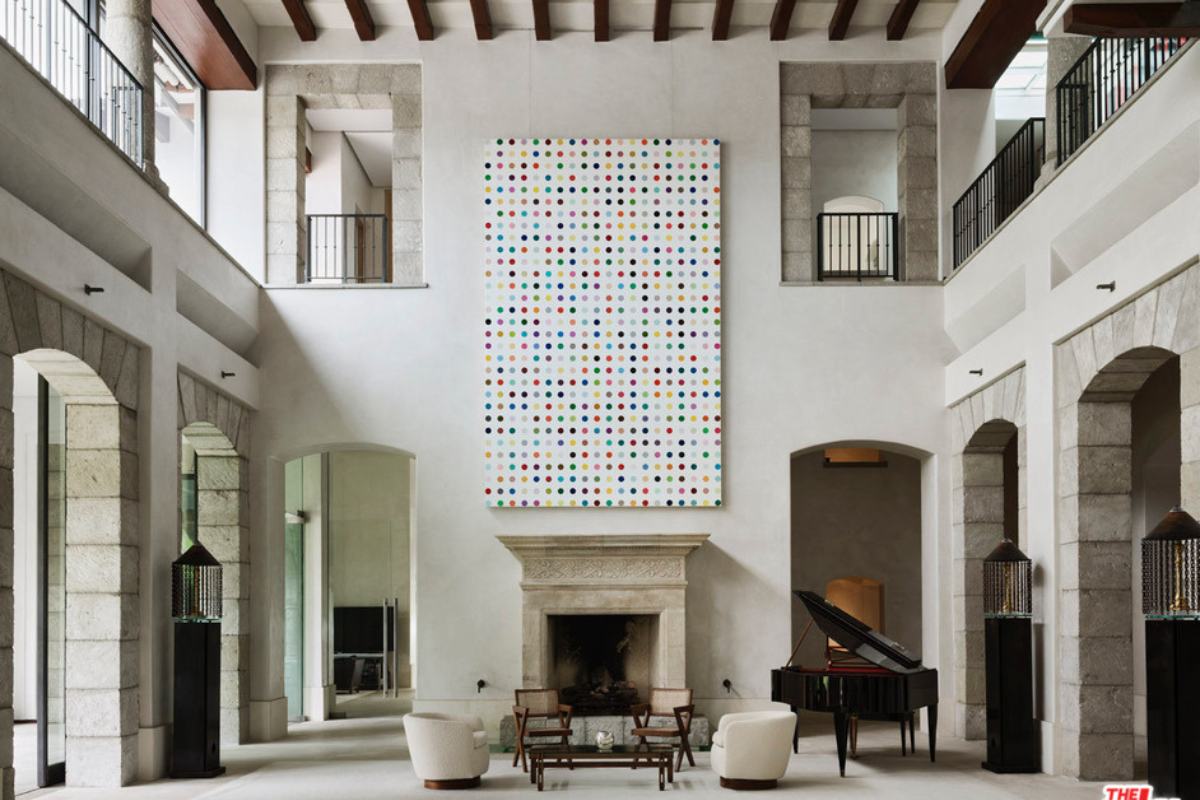 A living room with fireplace, white floors, piano, and a high ceiling.