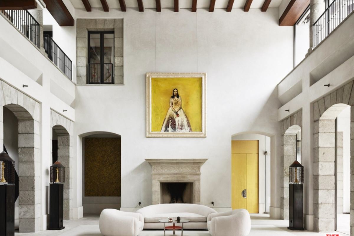 A living room with white floors, walls, painting and a high ceiling.