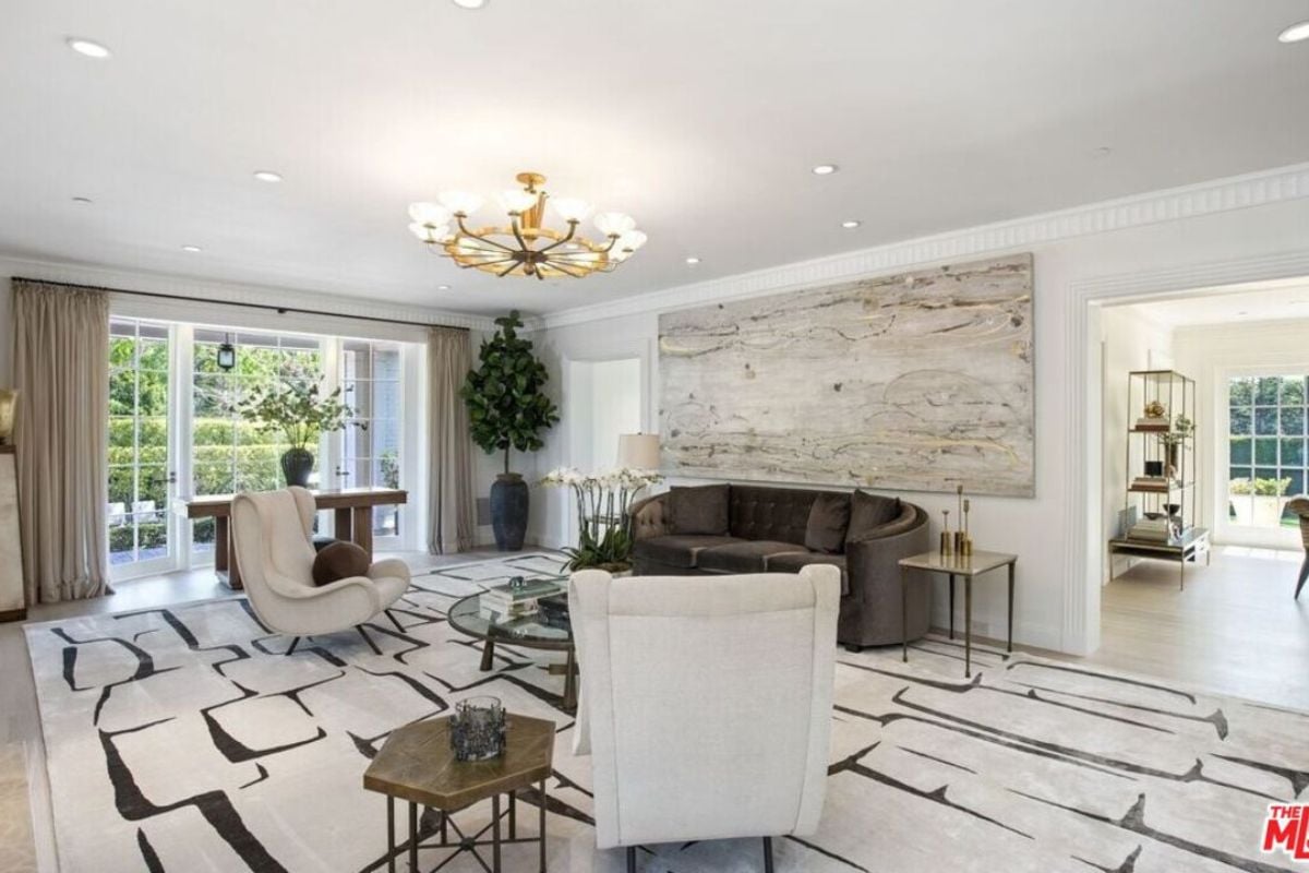 A living room with white walls and ceiling, a couch, chairs, and a chandelier.