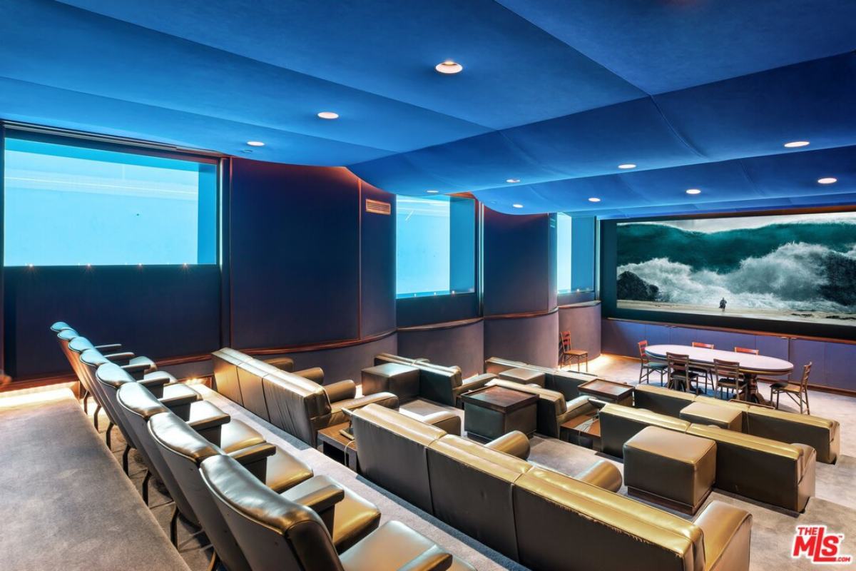 A home theater with a large screen, blue ceiling, chairs, and table.