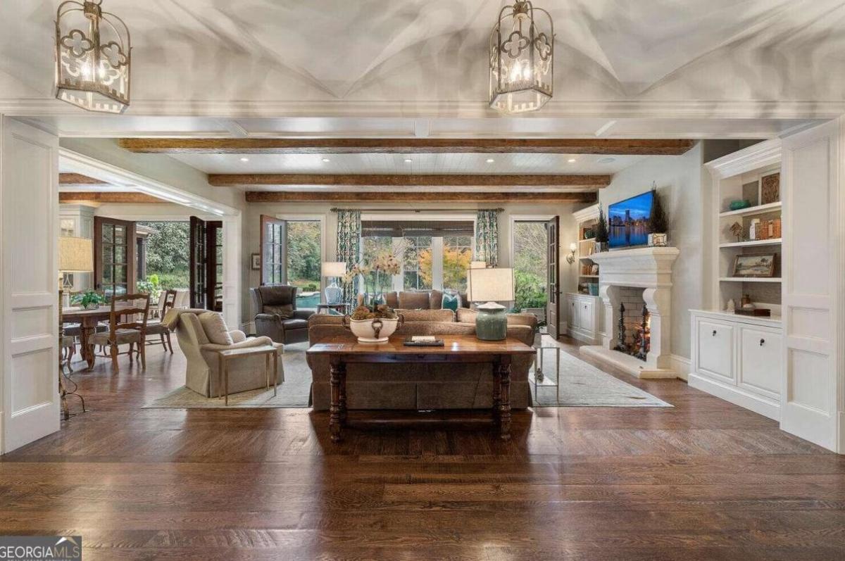 Living room with couches, open beam ceiling and a fireplace.