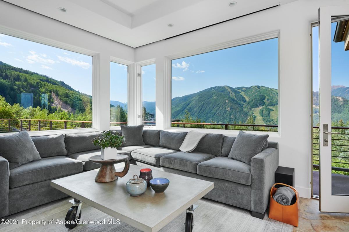 Living room with a large couch and large glass windows.