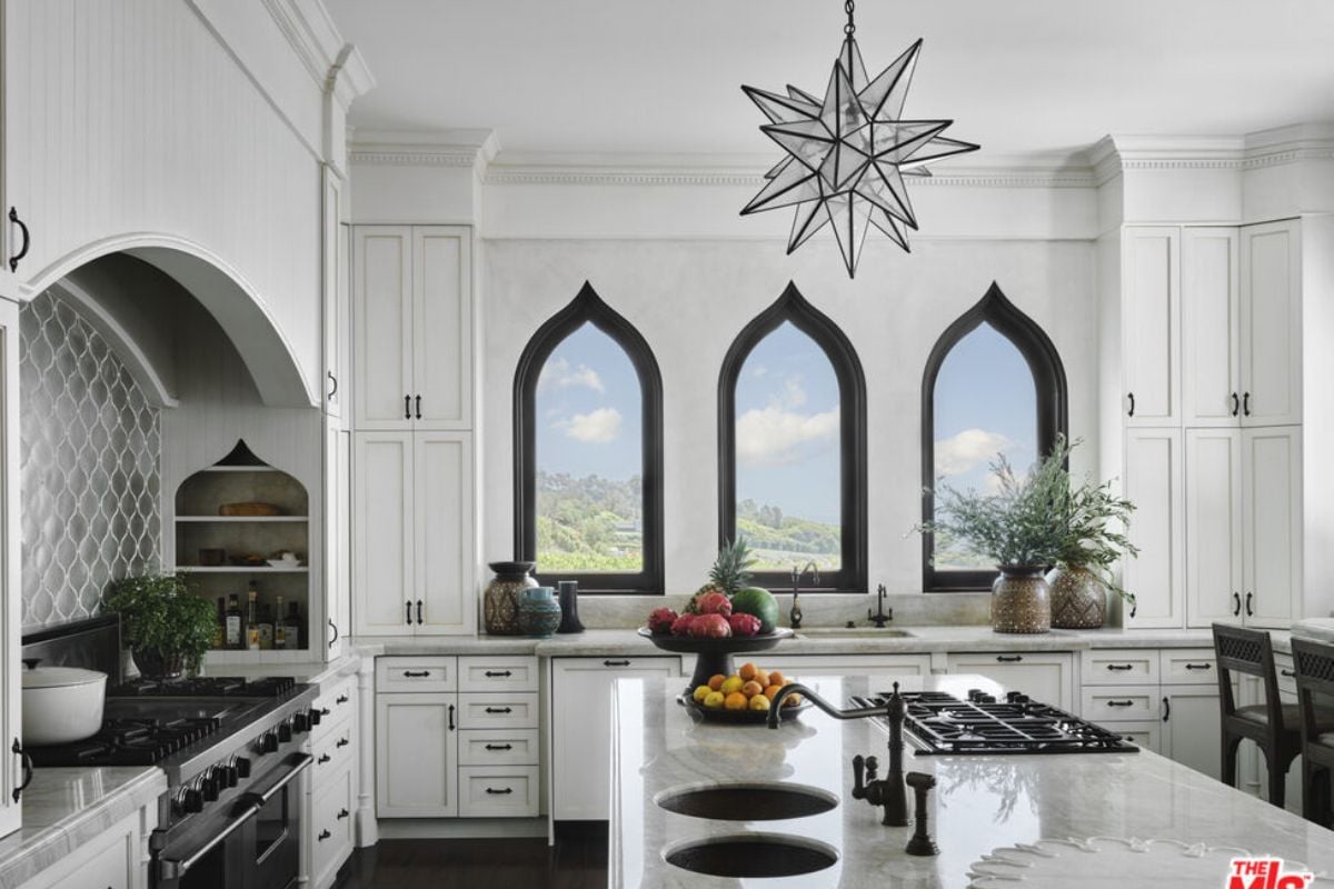 A kitchen with white walls and ceiling, white cabinetry, and a center island.
