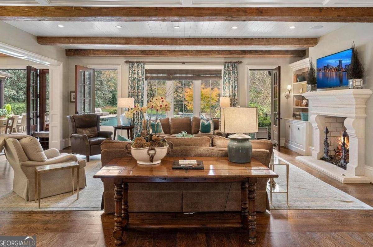 Living room with couches, open beam ceiling and a fireplace.
