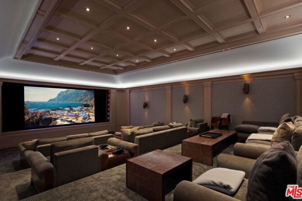 A home theater with couches, small tables, and a beamed ceiling.
