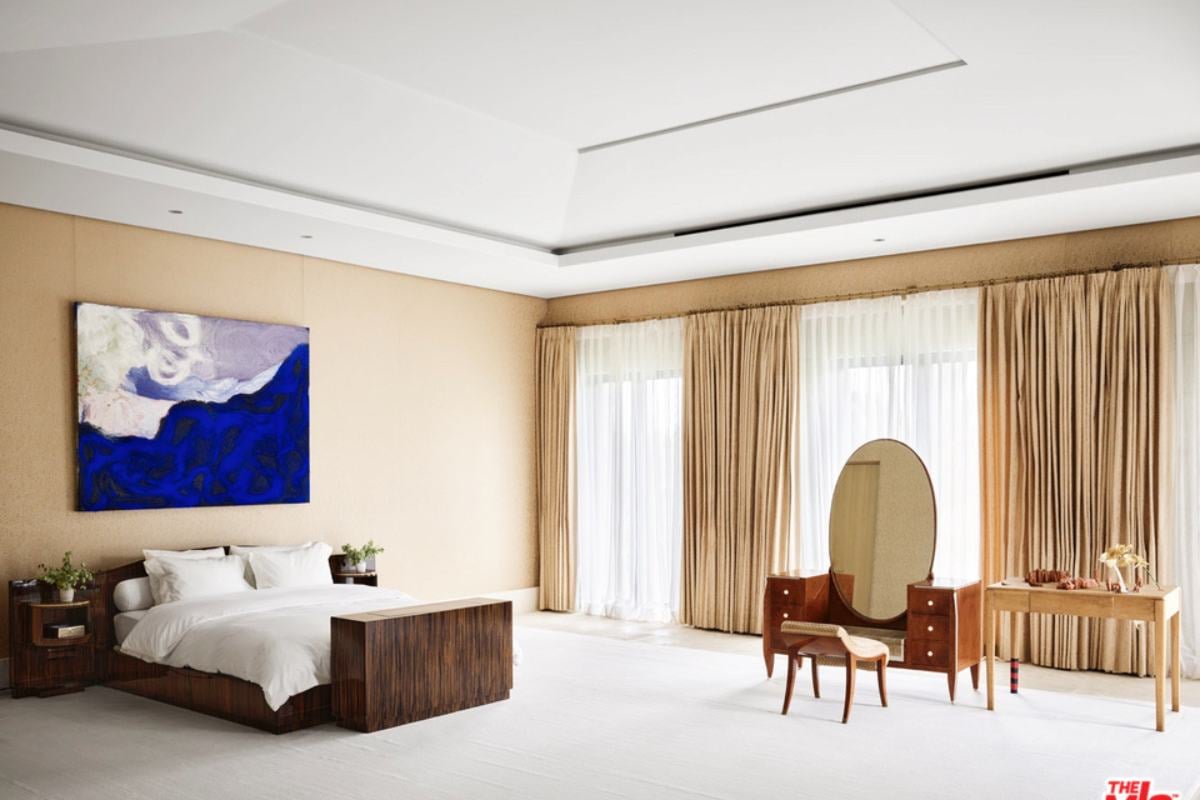 A bedroom with white floor and ceiling, featuring a painting hanging on the wall, a bed, a mirror, and a chair.