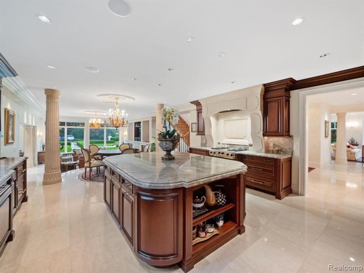 Kitchen with a large island, custom lights and a stove.