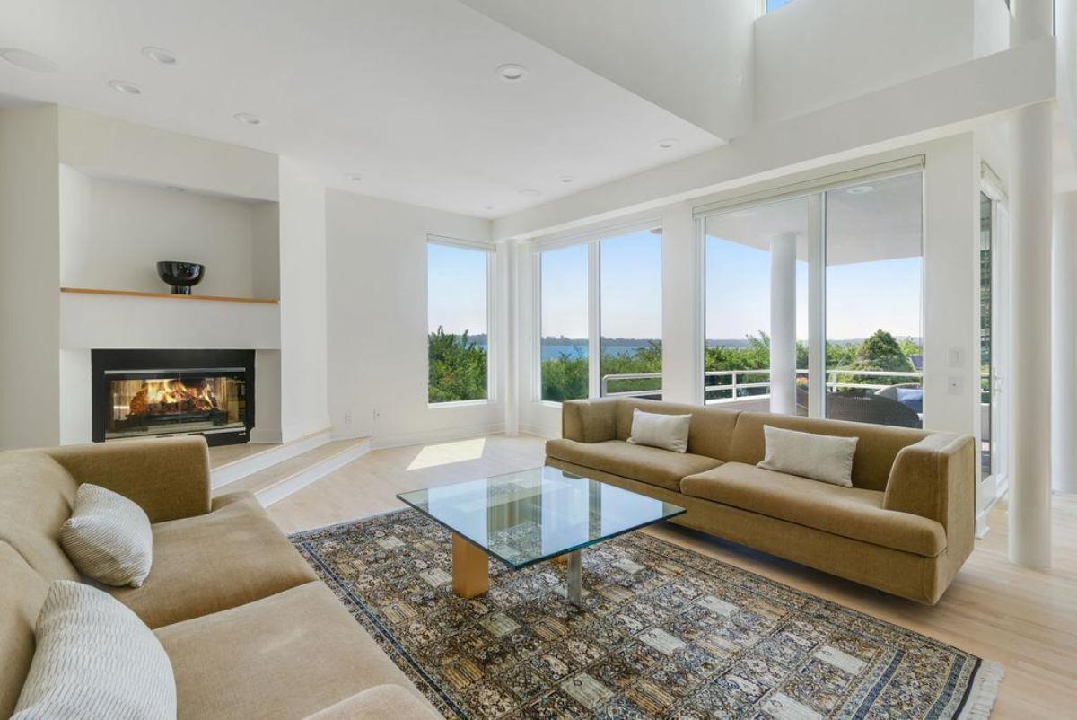 Living room with glass walls, fireplace and couches.
