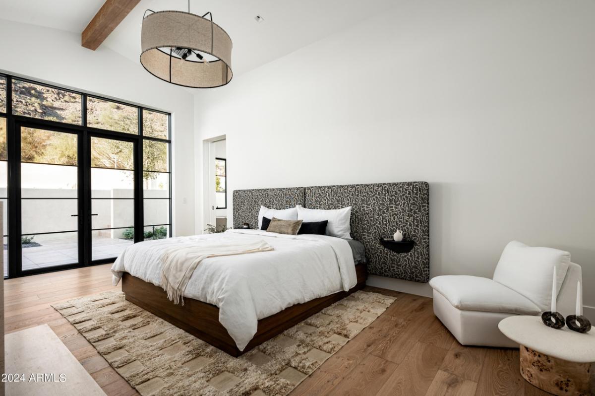 Bedroom with a large bed, large glass windows and wooden floor.