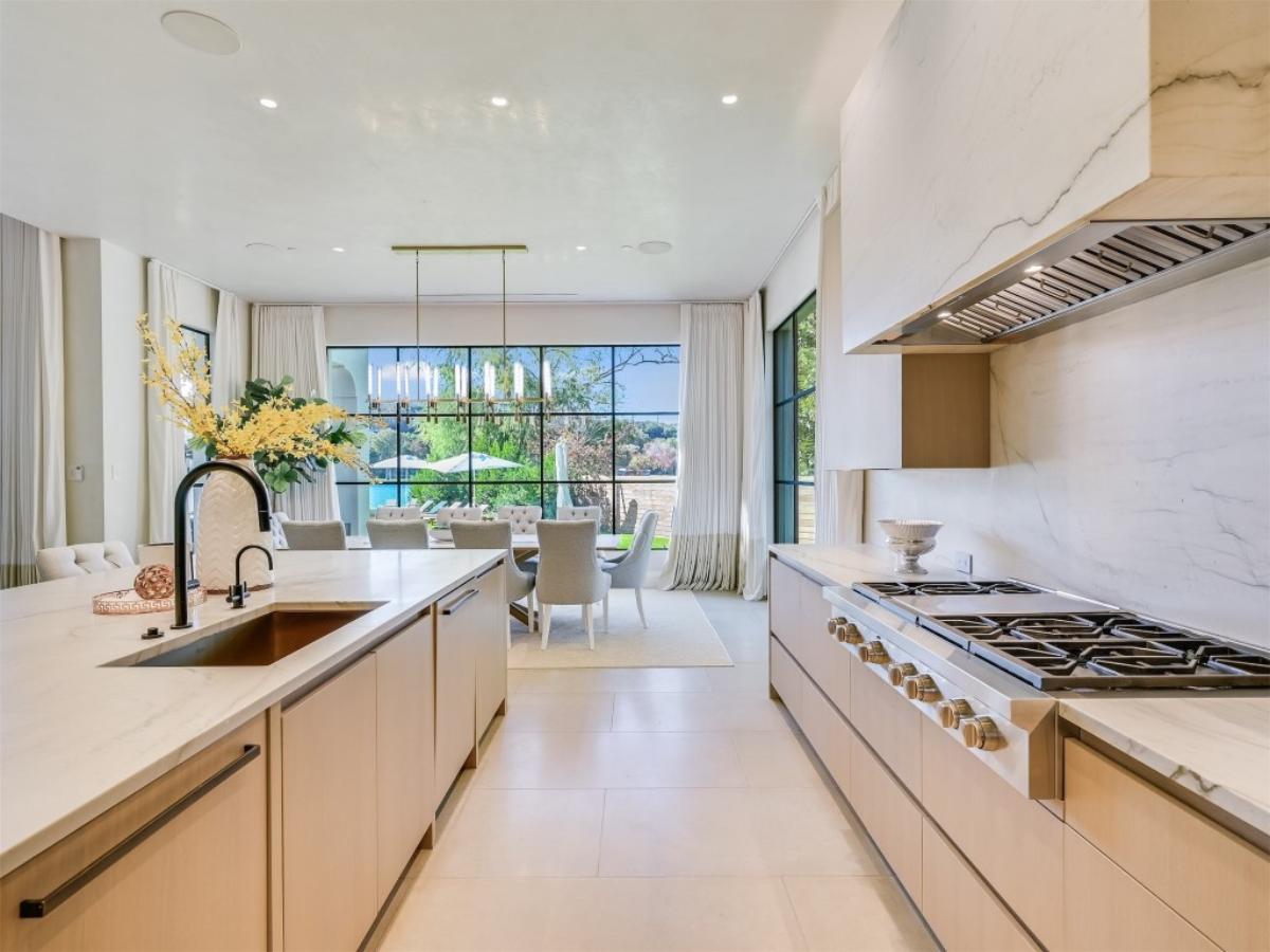 Kitchen with a large island, stove, custom lights and custom cabinets.