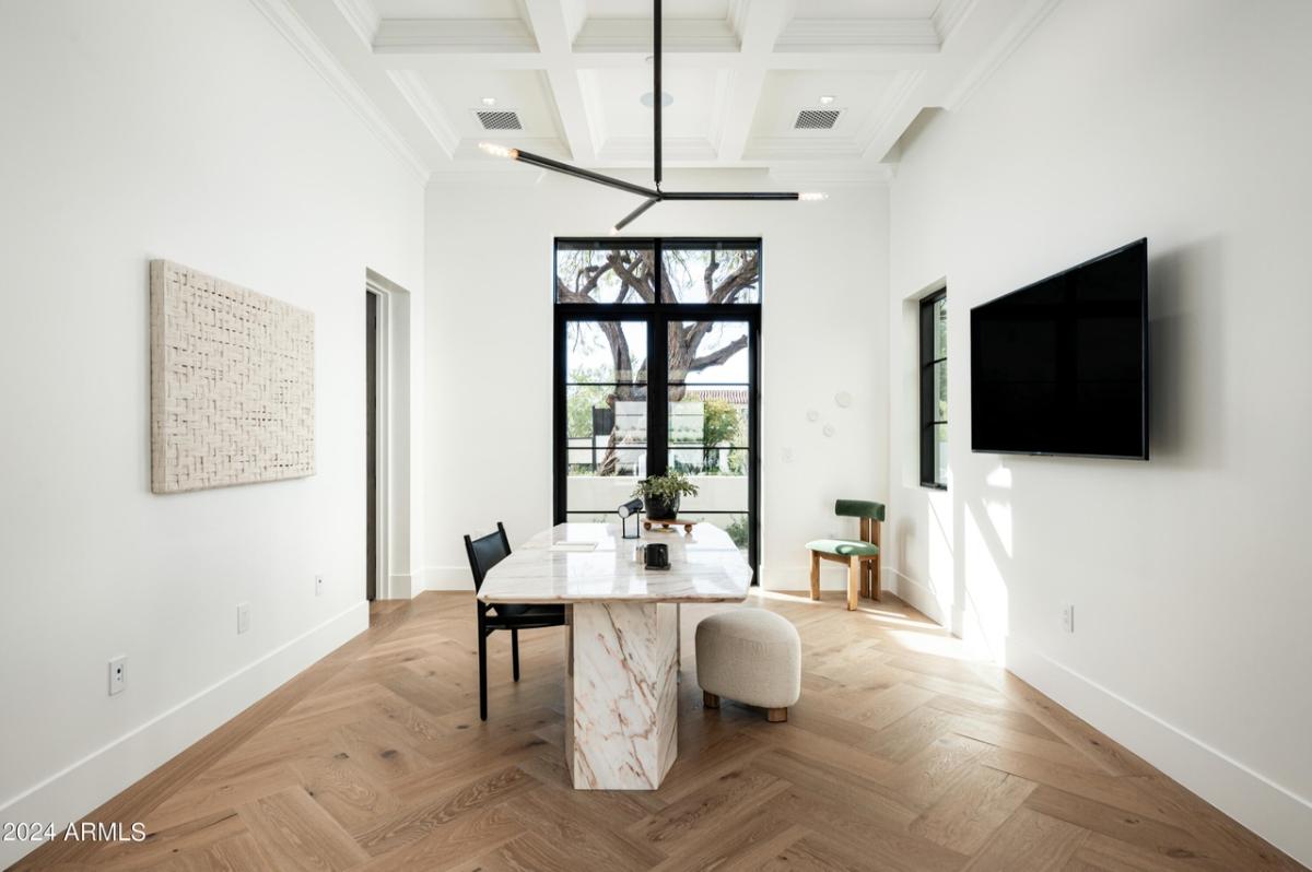 Home office with a desk, TV and glass doors.