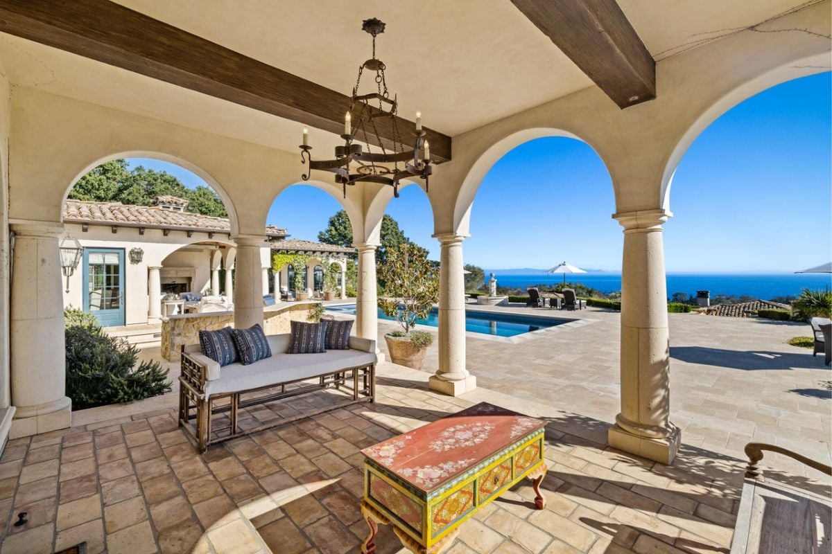 A porch with a chandelier, couch, and table.