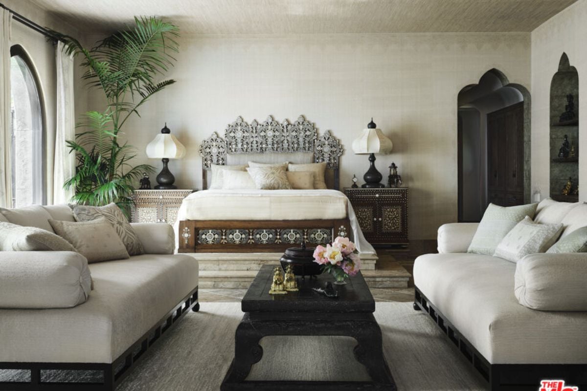 The bedroom, furnished with a bed and couches, showcases a coffee table, vase, and other furniture items.