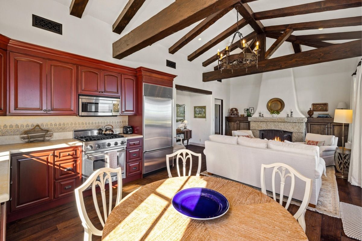 Guest house with a fireplace, couches, a dining table surrounded by chairs, and a small kitchen.