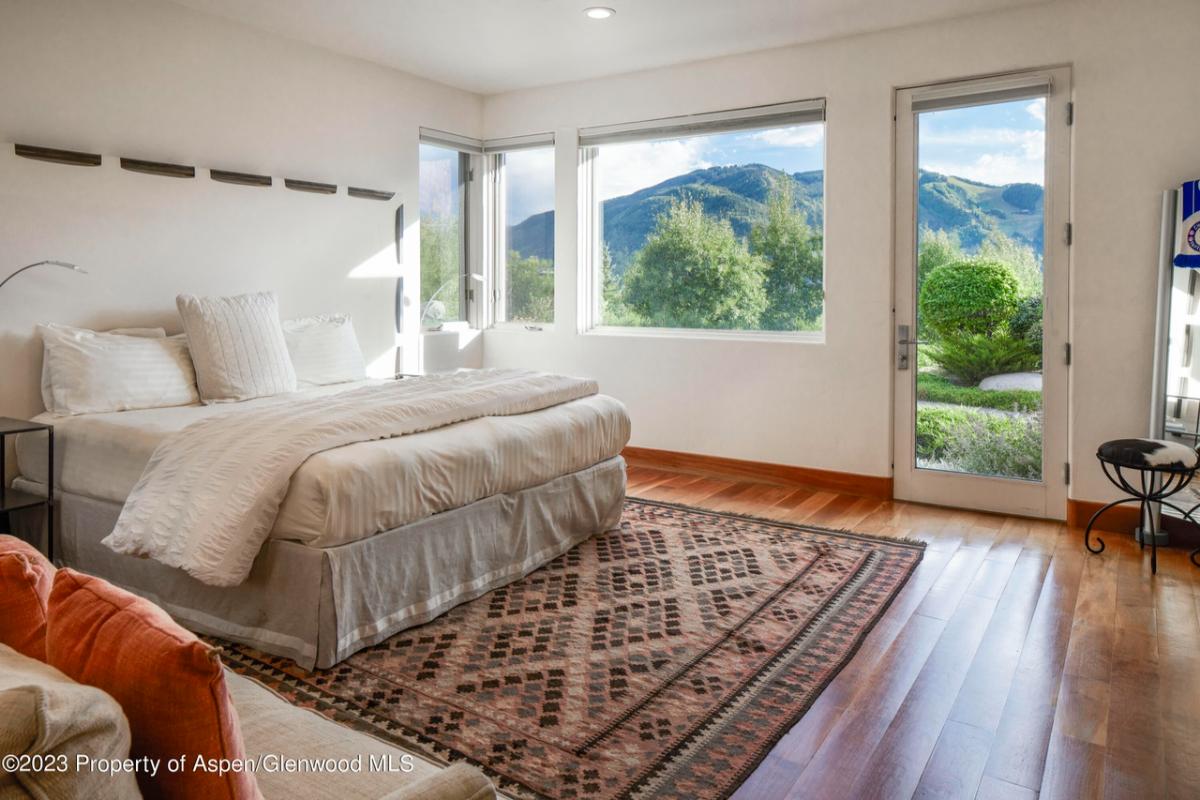 Bedroom with a large bed, glass windows and a glass door.