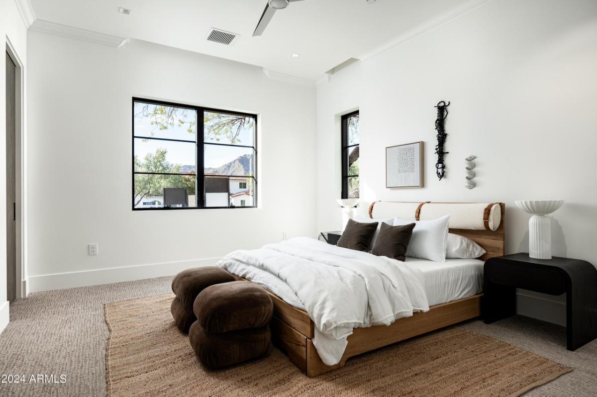 Bedroom with a large bed, carpet flooring and glass windows.