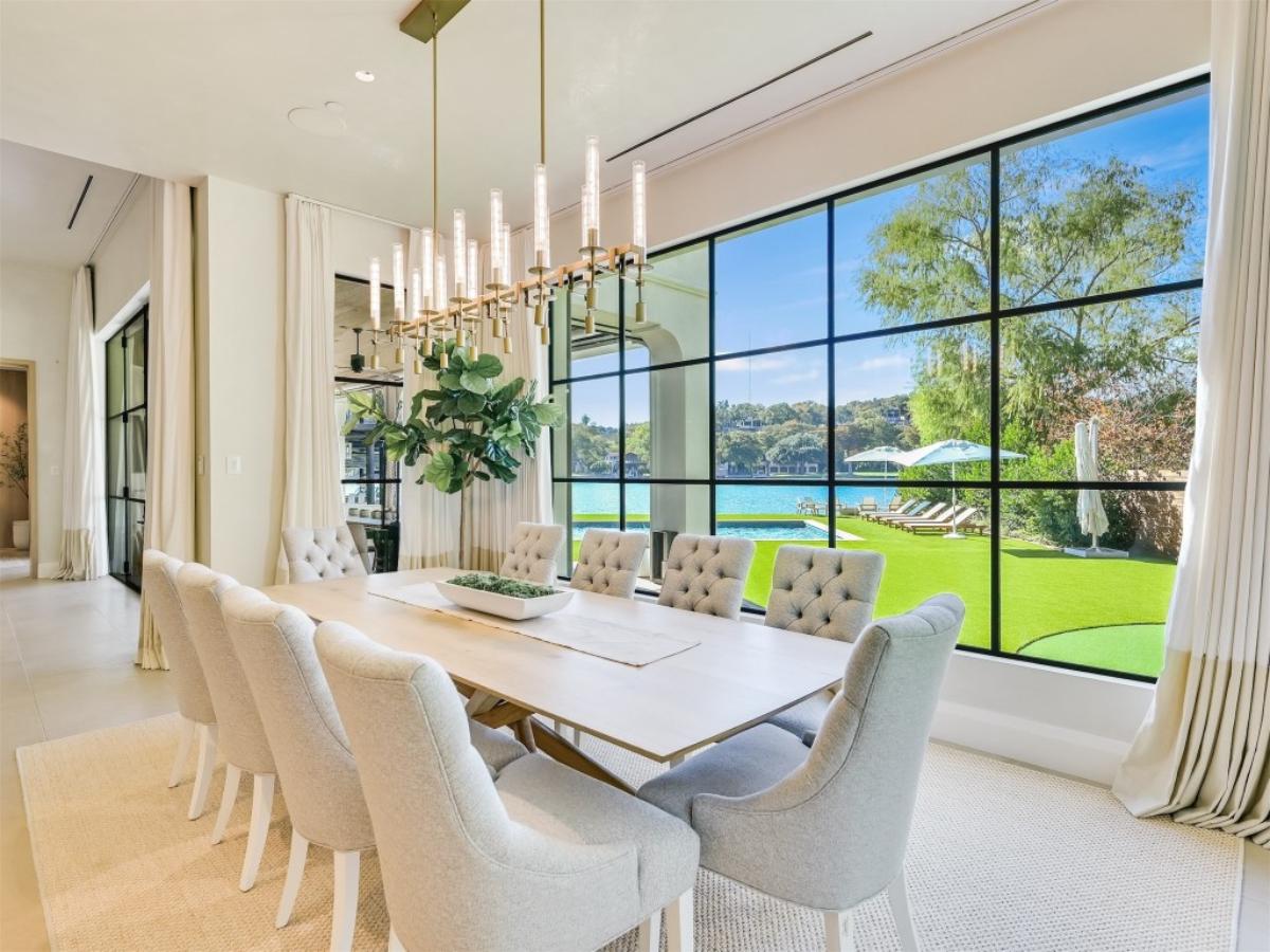 Dining room with a table, chairs and glass walls.