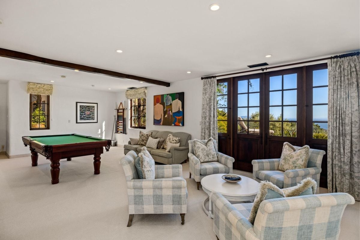 An entertainment room with a pool table, chairs, and white ceilings and walls.