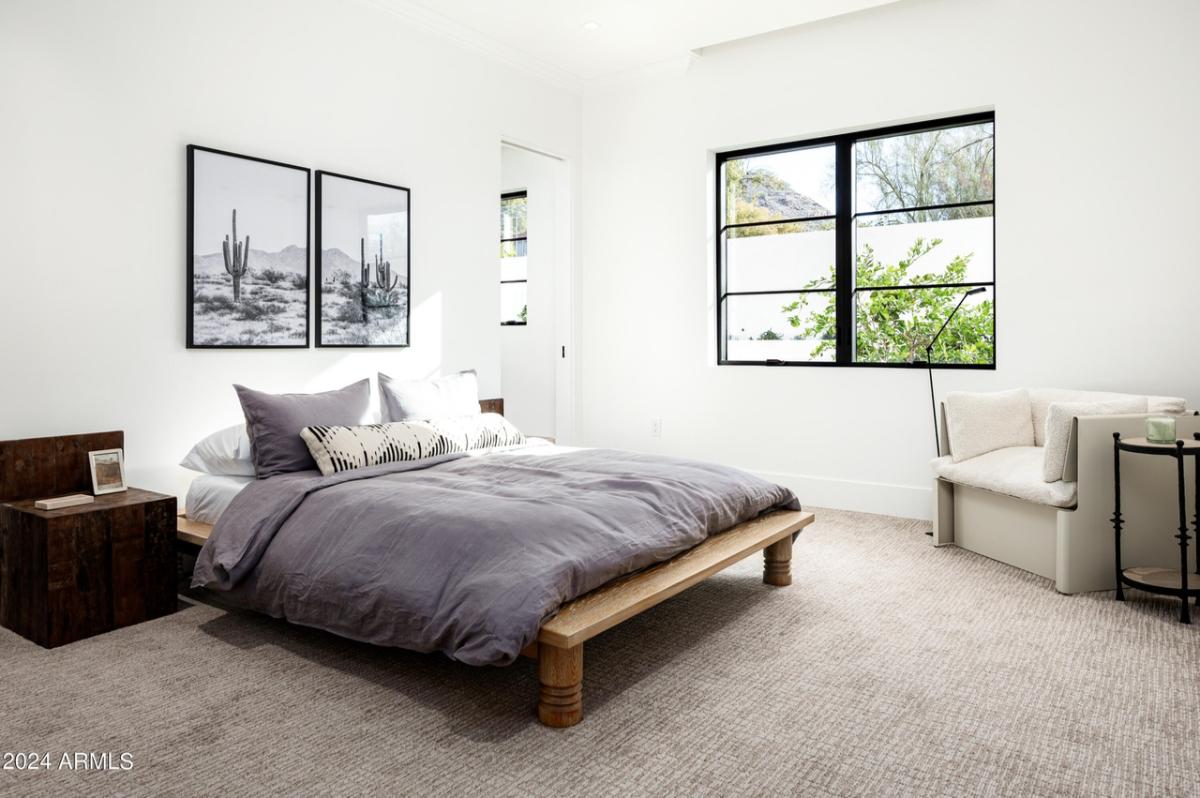 Bedroom with a large bed, carpet flooring and glass windows.