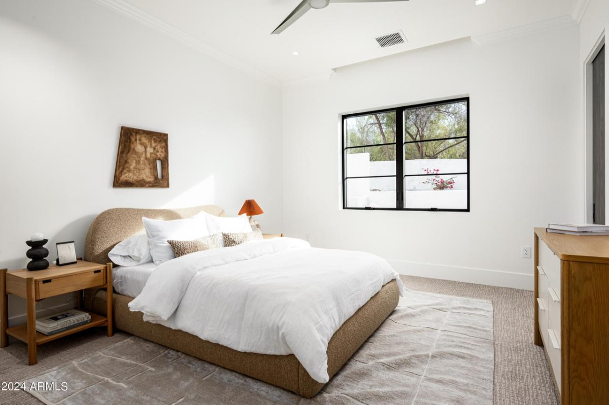 Bedroom with a large bed, carpet flooring and glass windows.