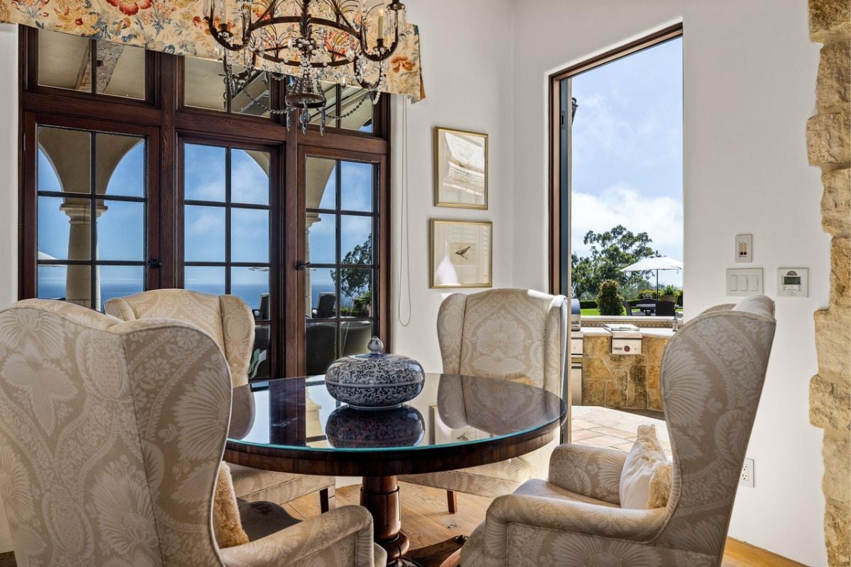 A breakfast nook with a chandelier and a table surrounded by chairs.