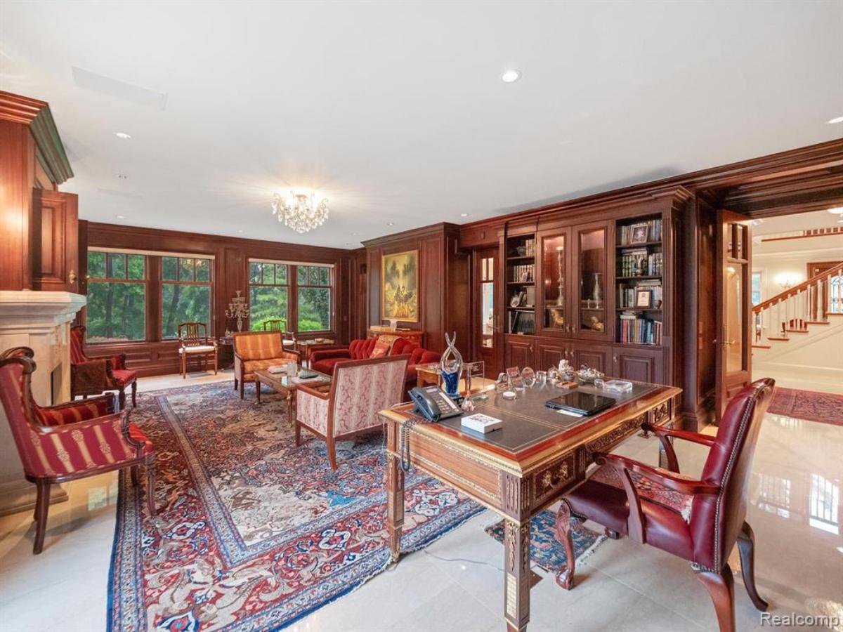 Home office with a desk, chairs, custom lights, bookshelves and a large rug.