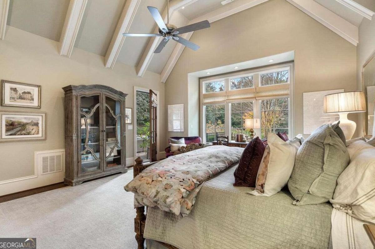 Bedroom with a large bed, carpet flooring and glass windows.